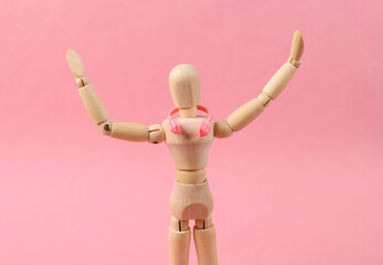 Wooden puppet with headphones on a pink background. Music lover