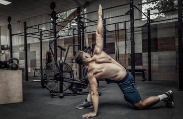 Young muscular man practicing muscle stretching in modern health club