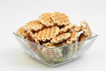 Belgian waffles in a glass bowl. holiday cookies on a white background. fresh baking concept. sweet desserts on a light texture