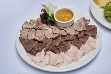 slicing of meat delicacies on a plate. boiled pork, ham, mustard