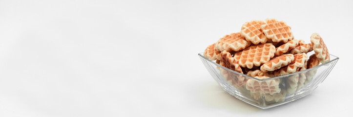 Belgian waffles in a glass bowl. holiday cookies on a white background. fresh baking concept. sweet desserts on a light texture
