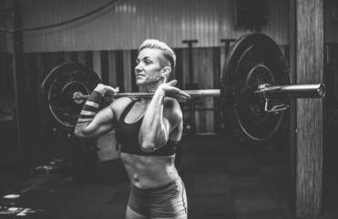 Naklejka na ściany i meble Athletic woman holding a barbell in modern cross gym. Functional training