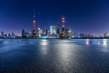 Empty asphalt road and city skyline with modern commercial buildings in Shanghai at night, China.