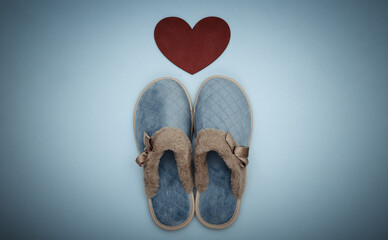 Cozy womens sleeping slippers and heart on a blue pastel background. Top view