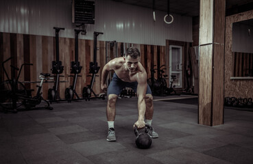 Obraz na płótnie Canvas Muscular powerful man exercising with heavy kettlebell in cross fit gym. Functional training with free weights