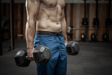 Muscular man holding heavy dumbbells in the gym