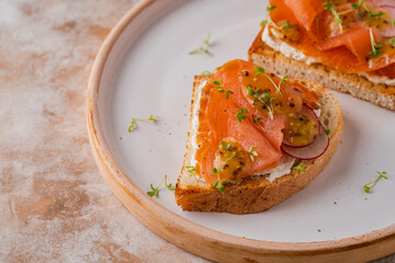 Two open sandwich, toast with smoked salmon, cream cheese, watercress, on white concrete table. Morning healthy breakfast with fish. side view, close up. clean eating.