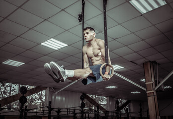 Muscular male gymnast exercising on gymnastic rings in a modern health club. Healthy lifestyle...