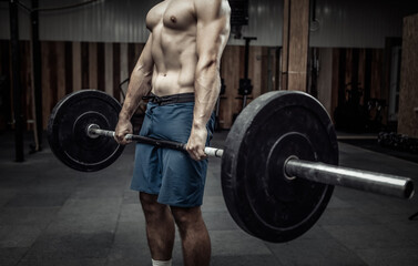 Fototapeta na wymiar Muscular bodybuilding man doing deadlift exercise with a heavy barbell in a modern health club. Bodybuilding and Fitness