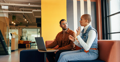 Two young businesspeople having an important discussion in an office lobby