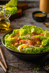 Salmon salad - smoked salmon hard boiled eggs, olives, watercress, sesam and green vegetables on dark brown table. Healthy food. Clean Eating. Paleo diet.