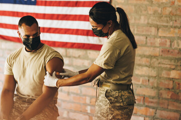 Nurse applying a band aid to a soldier's arm after vaccination