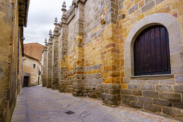 Alley next to the medieval cathedral with tall windows and doors in the city of Avila, Spain.