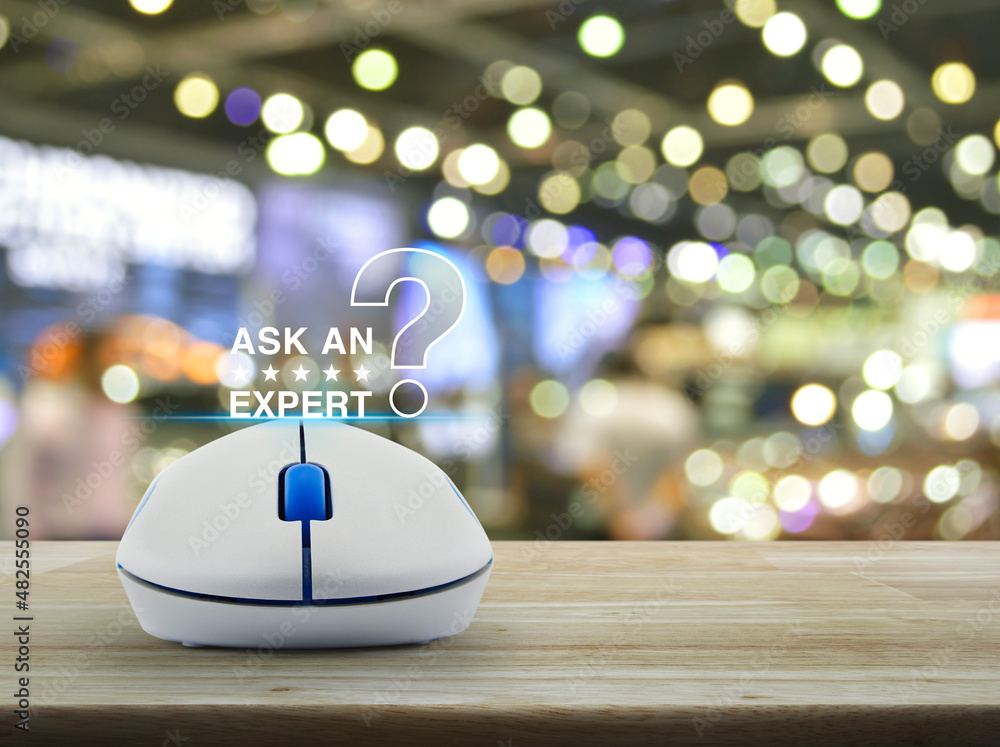 Poster ask an expert with stars and question mark sign icon with wireless computer mouse on wooden table ov