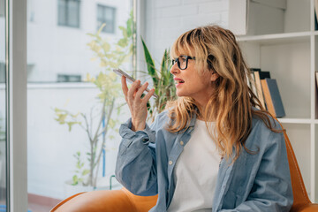 woman at home sending voice message with mobile phone