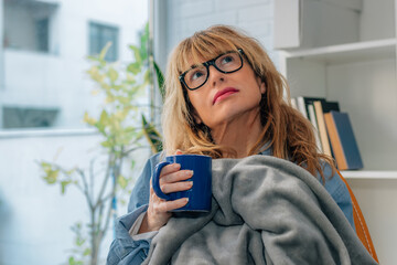 pensive home woman with blanket and cup
