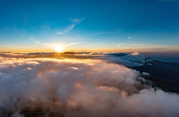 Sun shining brightly above white fluffy clouds at sunrise