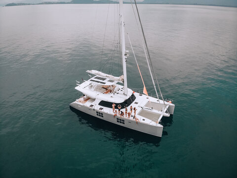 Picture of wonderful dancing girls in swimsuits on a luxury white yacht on the turquoise sea. Photo from a bird's-eye view. Enjoy vacation. Party at the sea. The concept of relaxation.