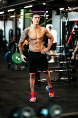 Fototapeta na wymiar Muscular man posing perfect body at gym. Portrait of professional athlete working out