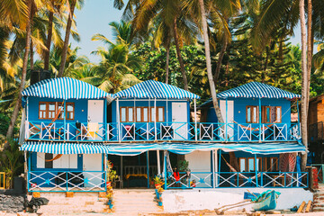 Canacona, Goa, India. Famous Painted Guest Houses On Palolem Beach Against Background Of Tall Palm Trees In Sunny Day.Canacona, Goa, India. Famous Painted Guest Houses On Palolem Beach Against - obrazy, fototapety, plakaty