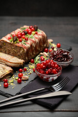 Traditional French terrine covered with bacon on dark wooden background with Christmas decorations