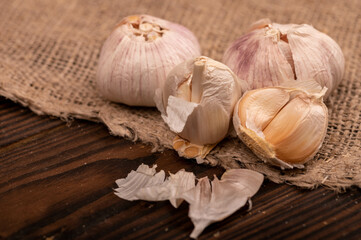 Heads of young garlic on a table covered with burlap, close-up, selective focus.