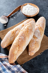 Still life with French fresh bread baguettes on a cutting board and wheat, shallow dof