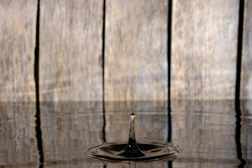 Obraz na płótnie Canvas Splash and ripples on water from fallen raindrop on wooden background.