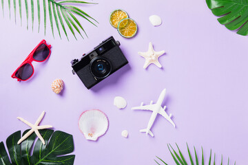 Top view flat lay mockup of camera films, airplane, sunglasses, leaves, starfish beach traveler accessories on a purple background with copy space, Business trip, and vacation summer travel concept