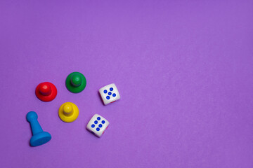 Colored game chips and playing cubes laid out on a purple background: entertainment, games at home for the whole family, the concept of board games. Board game. Table games