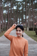 Happy woman in sweater traveling in pine tree forest, tourist visit at Doi Bo Luang, Chiang Mai, Thailand, Landmark and popular for tourist attractions. Vacation and journey concept