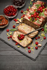 Traditional French terrine covered with bacon on dark wooden background with Christmas decorations