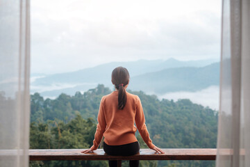 Happy woman relaxing and looking mountain view at countryside home or homestay in the morning. Vacation, blogger, SoloTravel, journey, trip and relaxing concept
