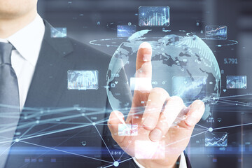 Close up of businessman hand pointing at creative glowing globe hologram with forex charts and graphs on blurry background. Trade, big data, stock, global business and finance concept. 