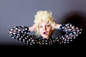 Curly girl - blonde in a blouse with polka dots like a clown on a black background