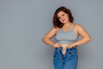 weight loss and overweight problem. a fat woman in a tank top and jeans is trying to button up or...