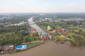 Aerial top view of a dam gate with forest trees in urban city, Nonthaburi town, Thailand.