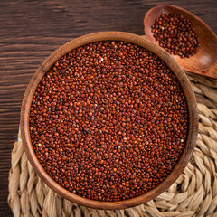 Organic red quinoa in a bowl on wooden table background.
