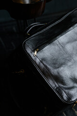 Leather black travel bag, on a black wooden floor