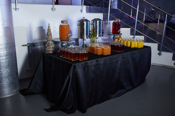 Catering, glasses with juice and thermopots stand on a table with a dark tablecloth and New Year's decor