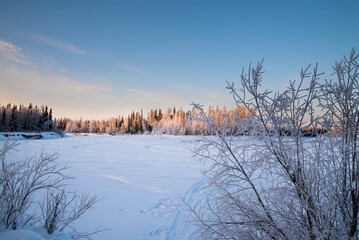 Frozen river in winter forest at sunset, winter landscape