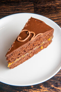 Chocolate Austrian dessert Sacher with apricot jam. One slice of traditional Sacher cake served on a white plate