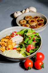 Traditional caesar salad in a white bowl on a dark gray table background. Selected focus.