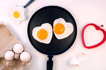 Heart shaped fried eggs on a pan, white background, top view. Valentines day breakfast idea. 
