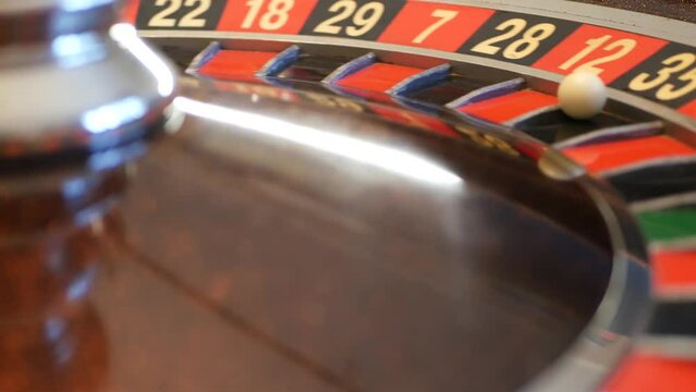 Ball on wooden french roulette table in casino. Wheel spinning, turning or rotating. Odd and even numbers, black, red and zero sectors. Bets in game of chance. Money playing, gambling or risky betting