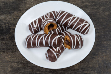 Cookies with striped chocolate glaze and jam filling on dish