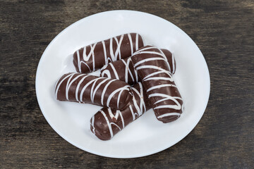 Cookies with striped chocolate glaze on dish on black surface