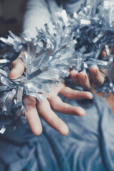 Hands holding christmas silver garland to home decor