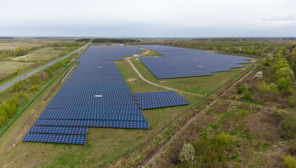 Ground-mounted solar power station next forest, aerial panoramic view