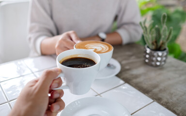 Closeup image of a couple people clinking coffee cups together in cafe